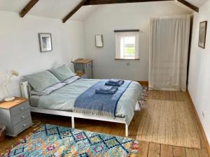 1 dormitorio con cama, mesa y ventana en Barn conversion in Zennor en St Ives