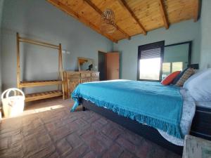 a bedroom with a large bed with a blue bedspread at LA CASITA in Sierra de la Ventana