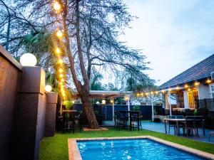 un patio trasero con piscina y un árbol con luces en New England Guest House by Ilawu en Pietermaritzburg