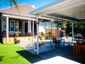 pérgola blanca sobre un patio con mesa en New England Guest House by Ilawu en Pietermaritzburg