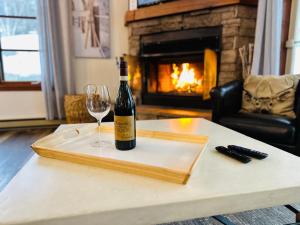 Le Plateau by Tremblant Vacations في مونت تريمبلانت: زجاجة من النبيذ وكأس على الطاولة