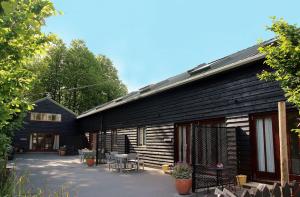 a wooden building with tables and chairs in front of it at Maplescombe in Alton