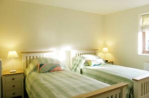 two beds in a small bedroom with two lamps at Maplescombe in Alton