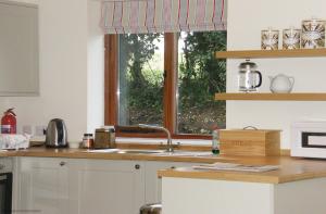 uma cozinha com um lavatório e uma janela em Maplescombe em Alton