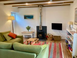 a living room with a green couch and a fireplace at Barn conversion in Zennor in St Ives