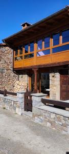 un edificio de piedra con muebles de madera, ventanas y puerta de madera en Casa Rural Ubales, 