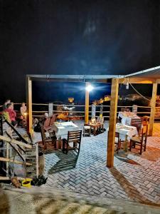 a patio with tables and chairs at night at Kaza Ladera in Seladinha