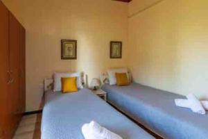 - 2 lits dans une chambre avec des draps bleus et des oreillers jaunes dans l'établissement Kiki’s Beautiful House On Famous Village Pentati, à Pentátion
