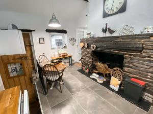 sala de estar con chimenea de piedra y reloj en la pared en Swallow Cottage - A Cosy Retreat Near Snowdonia and the Coast, en Abergele