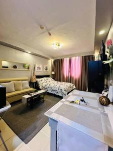 ein Wohnzimmer mit einem Sofa und einem Bett in einem Zimmer in der Unterkunft Yulee’s Comfortable Home Seakyung Village condo in Lapu Lapu City
