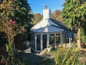 a greenhouse in a garden with trees and flowers at Swallow Cottage - A Cosy Retreat Near Snowdonia and the Coast in Abergele