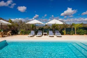 a group of chairs and umbrellas next to a swimming pool at Design Chalet in Albufeira With Private Pool in Albufeira