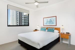 a white bedroom with a large bed with blue pillows at Republic Apartments Brisbane City in Brisbane +54 photos