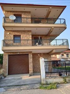 a large building with a balcony and two garage doors at Το πέτρινο σπίτι in Nea Plagia