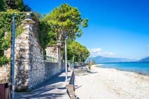 a bench on a beach next to a stone wall at Perla Top Floor Apartment in Sirmione