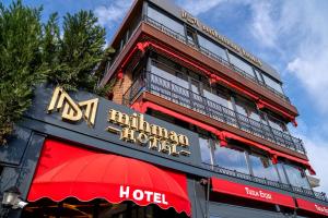 a building with a hotel sign and a red umbrella at Mihman Hotel in Tuzla