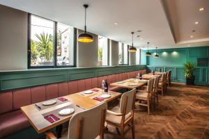 a restaurant with wooden tables and chairs and windows at Eliada Hotel in Kusadası