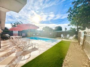 eine Terrasse mit Stühlen, einem Sonnenschirm und einem Pool in der Unterkunft Luxury Villa 3 Blocks from the Beach with Pool a Fire Pit and Outdoor Oasis in Cape Canaveral