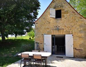een tafel en stoelen voor een gebouw bij Maison climatisée avec jacuzzi à 10 min de Sarlat in Sarlat-la-Canéda