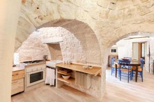 een keuken met een stenen muur met een tafel en stoelen bij Trulli of Stars in Ostuni