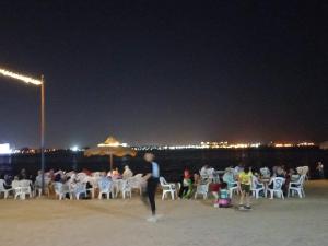 eine Gruppe von Menschen, die nachts am Strand sitzen in der Unterkunft قرية النورس مكتب السعد in Ismailia