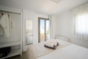 a white bedroom with a bed and a mirror at Kymo Luxury Suites Paros in Kolympithres