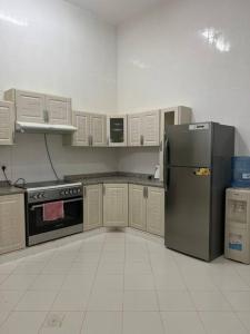 a kitchen with a stainless steel refrigerator and white cabinets at Masfout/hatta mountain villa in Sinādil