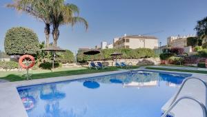 une piscine avec chaises et parasols dans un complexe hôtelier dans l'établissement Lovely Aldea Beach Apartment, à Manilva