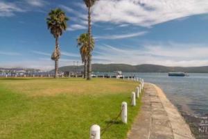 a grassy field with palm trees next to a body of water at Waterfront Apartment in Knysna