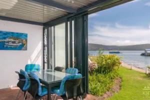 a glass table and chairs on a patio with a view of the water at Waterfront Apartment in Knysna
