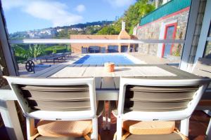 a table and two chairs on a balcony with a pool at Casa da Rainha Bungallow in Estreito da Calheta