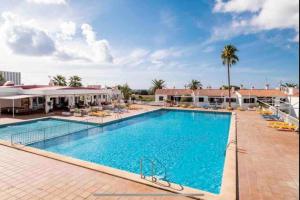 a pool at a resort with chairs and palm trees at Appartamento Giuliana in Son Bou