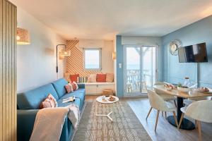 ein Wohnzimmer mit einem blauen Sofa und einem Tisch in der Unterkunft Résidence Pierre & Vacances Les Tamaris in Trouville-sur-Mer