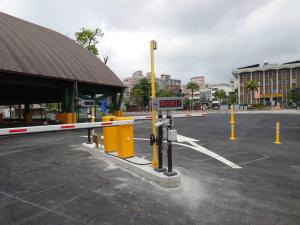 a parking lot with yellow barriers in front of a building at Michi Hotel - Luodong in Luodong