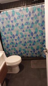 a bathroom with a toilet and a geometric shower curtain at Apartamento Granat cerca del aeropuerto y la zona cultural y gastronómica in Guatemala