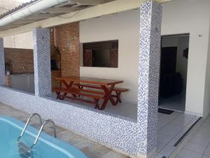 a pool with a wooden table and a picnic table at Casarão Em Pirangi Praia - RN in Parnamirim