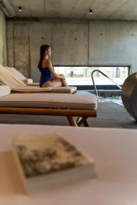 une femme assise sur un lit dans une pièce dans l'établissement Borralha Hotel, Restaurante & Spa, à Vila Real