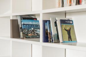a row of books sitting on a shelf at Spacious & modern 2 bed flat in Hoylake - Near to Royal Liverpool Golf Club in Hoylake