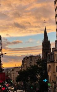 a view of a city with a church steeple at sunset at Chez les artistes de Ménilmontant in Paris