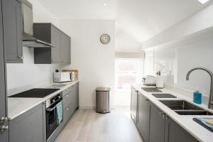 a white kitchen with gray cabinets and a sink at Spacious & modern 2 bed flat in Hoylake - Near to Royal Liverpool Golf Club in Hoylake