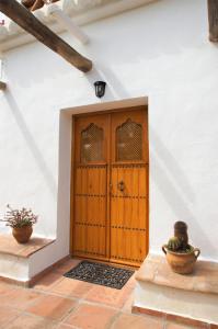 eine Holztür in einem weißen Gebäude mit zwei Topfpflanzen in der Unterkunft Casa del Cielo in Frigiliana