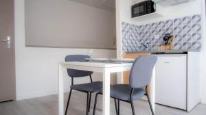 une cuisine avec une table blanche et des chaises bleues dans l'établissement Chez Thomas - Bel appartement à Poitiers !, à Poitiers