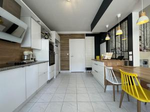 Coulaines的住宿－Havre de Vacances Piscine Reve au Mans，厨房配有白色橱柜、桌子和黄色椅子