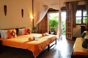 um quarto com uma cama grande com lençóis laranja em Karibu Entebbe em Entebbe