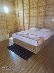 un grande letto in una camera con pavimento in legno di Goutham Guest House And Restaurant Hampi a Hampi