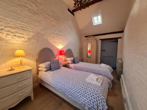 een slaapkamer met 2 bedden, een dressoir en een lamp bij The Long Cottage 6 in Flitcham