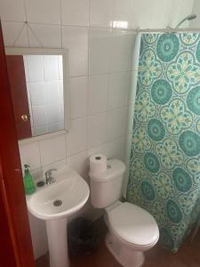 een badkamer met een toilet, een wastafel en een spiegel bij Cabaña colmo in Quintero