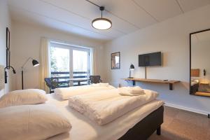 a room with three beds and a table and a television at Motel Apartments in Tønder