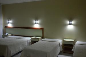 um quarto de hotel com duas camas e luzes na parede em Nanuque Panorama Hotel em Nanuque
