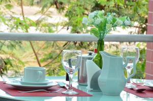 uma mesa com um vaso de flores, pratos e copos em Nanuque Panorama Hotel em Nanuque
